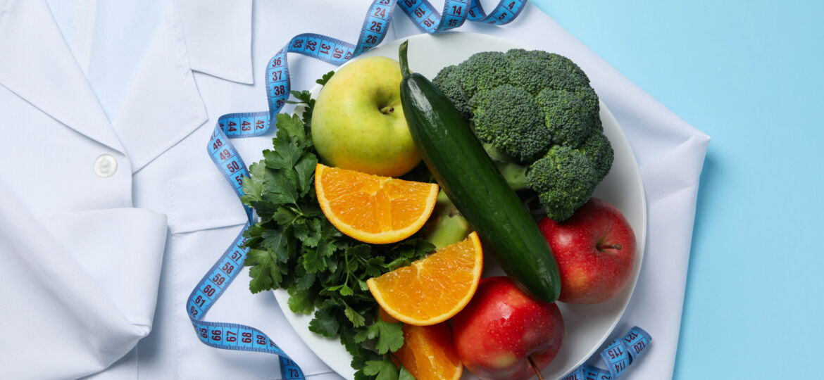 Doctors coat, healthy food and measuring tape on blue background