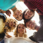 Group of happy business executives forming huddle in office